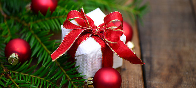 Weihnachtsgeschenk mit roter Schleife und Tannenzweig